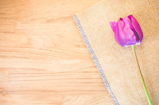 A high angle shot of a purple tulip on a piece of cloth on a wooden surface