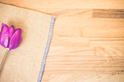 A high angle shot of a purple tulip on a piece of cloth on a wooden surface