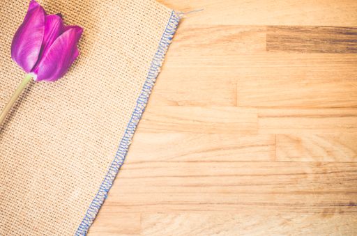 A high angle shot of a purple tulip on a piece of cloth on a wooden surface