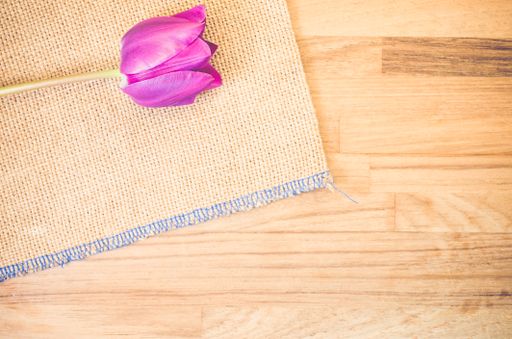 A high angle shot of a purple tulip on a piece of cloth on a wooden surface