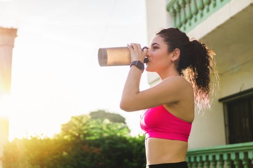 A closeup shot of young female drinking water after working out outdoors - healthy lifestyle concept