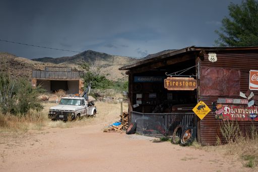 An old  a sixth generation Ford F-Series tow truck near a mechanic shop on the desert road