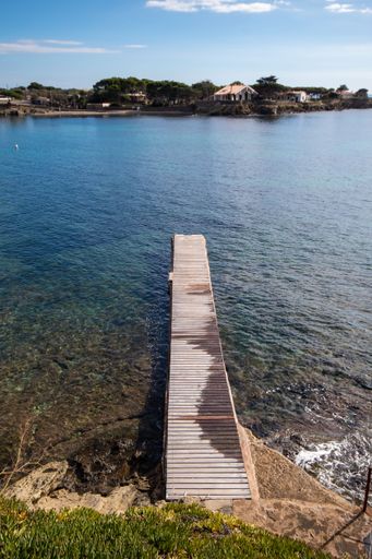Path with wooden planks over the sea in the town of Cadaques where tourists get off their boats.