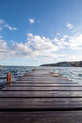 Path with wooden planks over the sea in the town of Cadaques where tourists get off their boats.