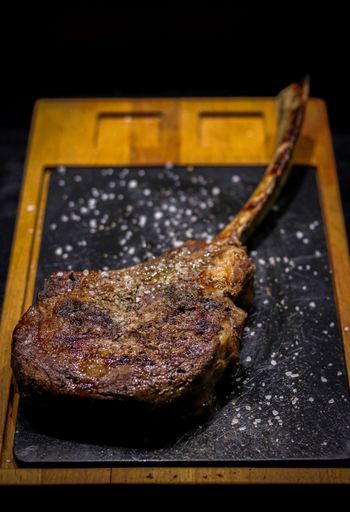A vertical closeup shot of a deliciously cooked rib eye steak on a black board
