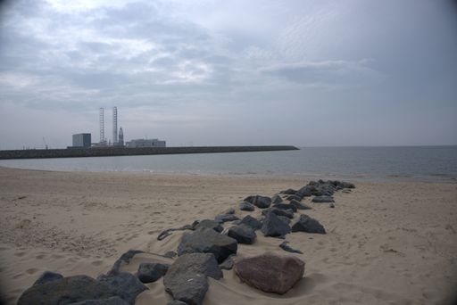 A scenic view of the sandy beach and the calm sea on a gloomy cloudy day