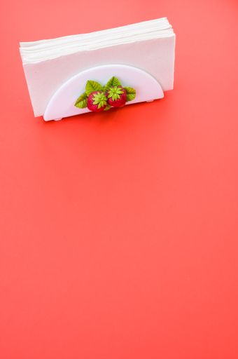 A vertical shot of a napkin holder with strawberry detail on peach background with space for your text