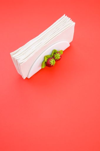 A vertical shot of a napkin holder with strawberry detail on peach background with space for your text