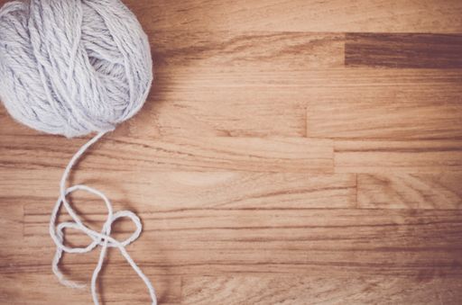 An overhead shot of a ball of yarn on a wooden surface with space for your text