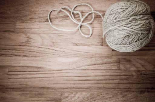 An overhead shot of a ball of yarn on a wooden surface in monochrome, with space for your text