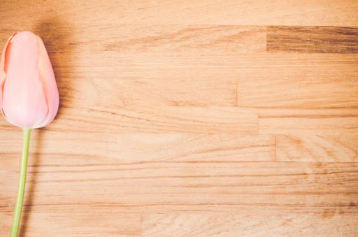 An overhead shot of a red tulip flower on a wooden table with space for your text