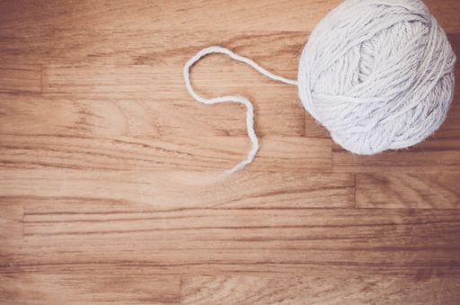 An overhead shot of a ball of yarn on a natural wood tabletop with space for your text