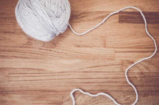 An overhead shot of a ball of yarn on a natural wood tabletop with space for your text