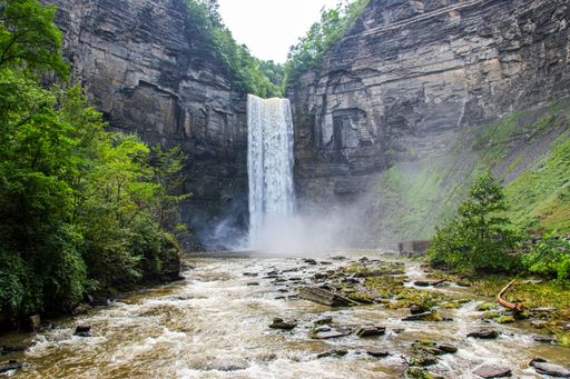 A flowing waterfall surrounded by cliffs and trees