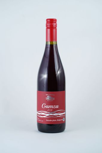 A bottle of red wine sitting on a pristine white table top against a plain white background
