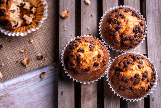A top view of the freshly baked cupcakes with chocolate chips on a wooden tray