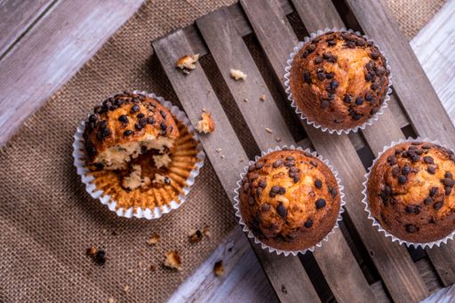 A top view of the freshly baked cupcakes with chocolate chips on a wooden tray
