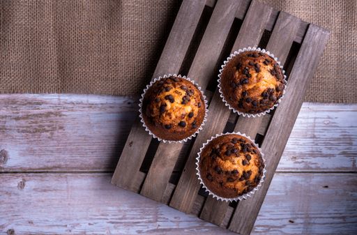 A top view of the freshly baked cupcakes with chocolate chips on a wooden tray