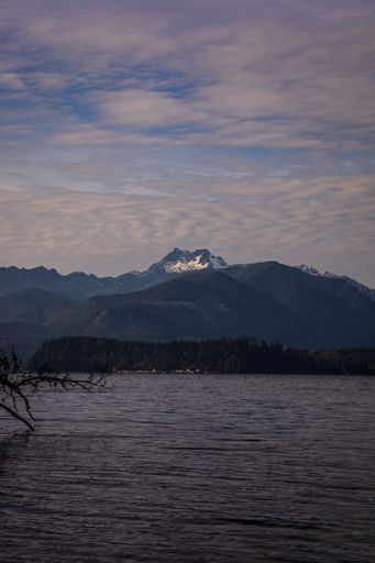 A vertical shot of a tranquil lake surrounded by forested mountains