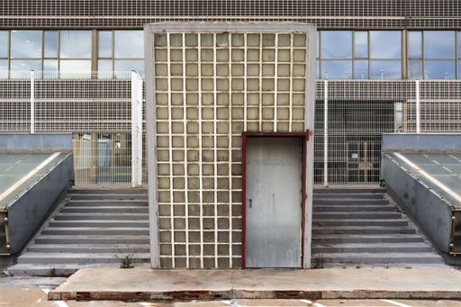 A view of a separate entrance in front of the building on the stairs with small square windows