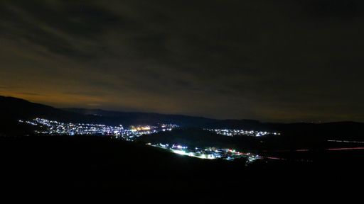 An amazing shot of an illuminated town in a mountain landscape during a deep sunset