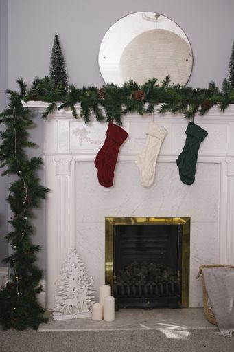 the vertical shot of socks hung from a green chain and the golden fireplace