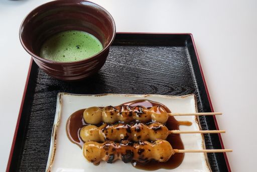 A closeup shot of sweet mochi and a cup of matcha tea on a dark tray