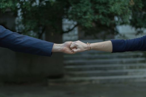 A closeup shot of a stylish couple reaching out and holding hands