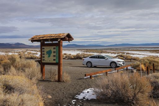 A car is parked at the Black Point Trailhead parking area on the north shore of Mono Lake.