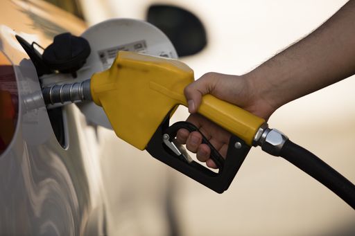 A white car at a gas station being filled with fuel