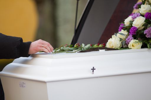 A closeup shot of a person hand on a casket with a blurred background