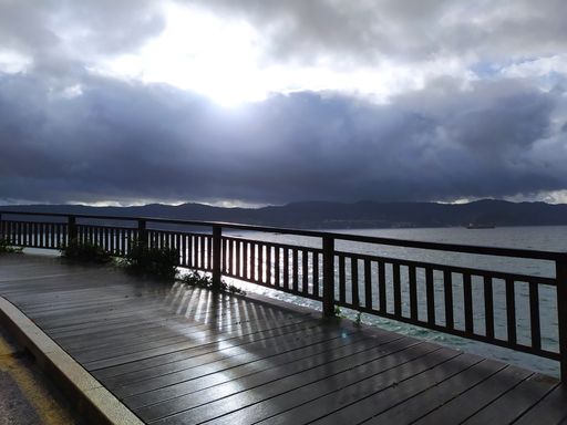A wooden dock on the sea under a cloudy sky and sunlight on a stormy day