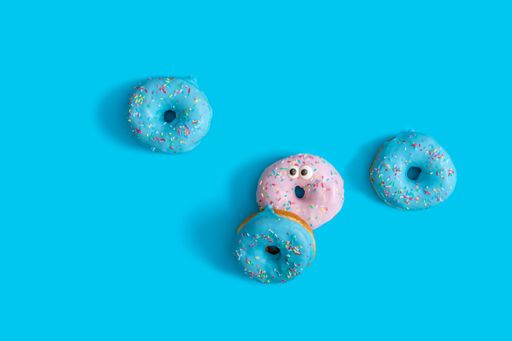 A top view of three blue and one pink donut on a blue background  - the concept of diversity