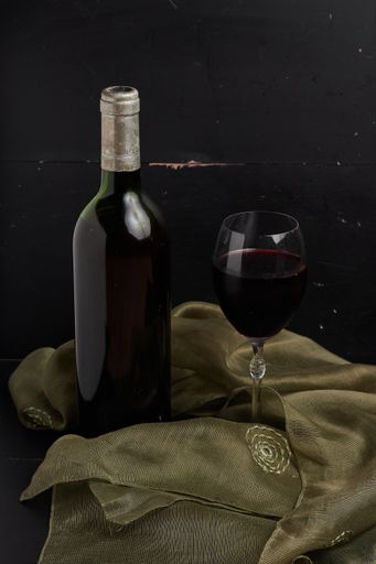 A vertical shot of a bottle of wine and a wineglass by a black background
