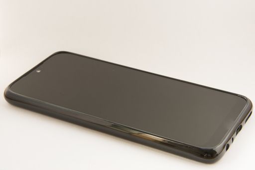 A closeup shot of a black smartphone with a black case on a white background
