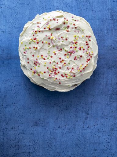 A vertical shot of a delicious carrot cake on a blue surface
