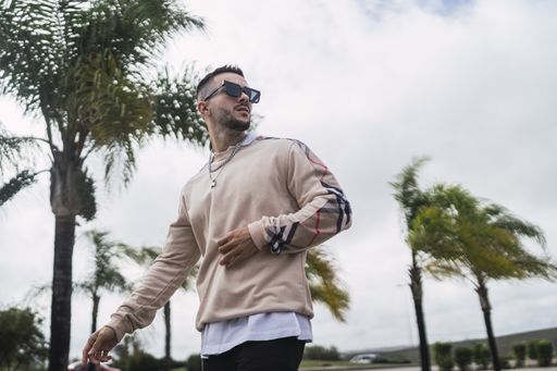 A closeup shot of a stylish young attractive man wearing a sweater over a shirt with necklaces