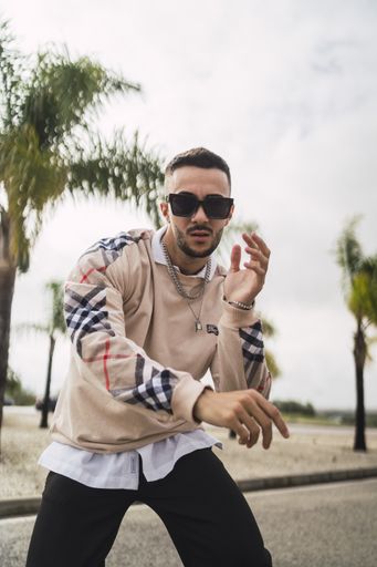 A vertical shot of a stylish young attractive man wearing a sweater over a shirt with necklaces