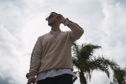A closeup shot of a stylish young attractive man wearing a sweater over a shirt with necklaces