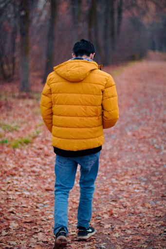 A vertical shot of a guy walking in a park on a cold autumn day in Bishkek, Kyrgyzstan