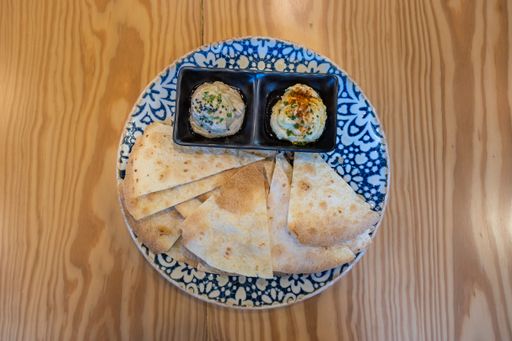 A top view of toasted tortilla and sauces on a plate laid on a wooden table