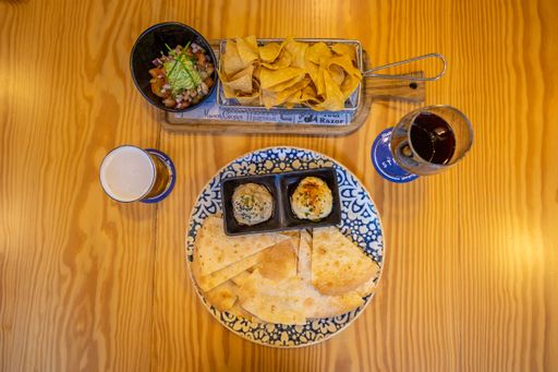 A top view of the toasted tortilla, sauces, chips, salad and a glass of wine on a wooden table