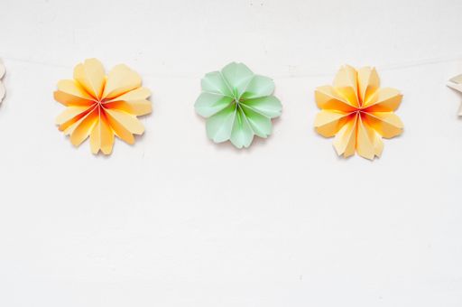 A top view closeup of flowers made out of colorful paper for decorations isolated on a white surface