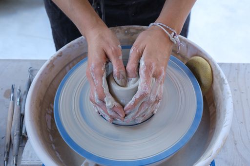 A closeup of a craftswoman's hands working on the potter's wheel