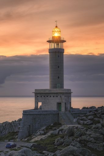 A vertical shot of a classic Punta Nariga lighthouse in Galicia, Spainduring sunset