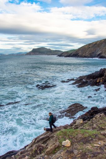 A vertical shot of a female and her dog standing by the stormy ocean