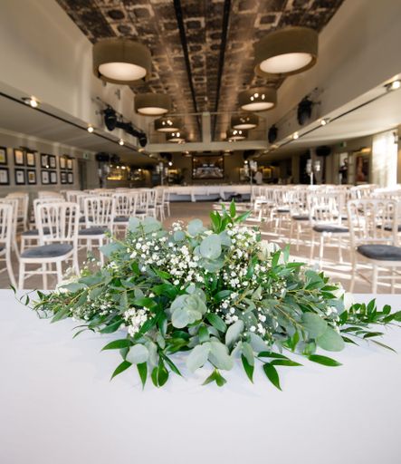 A closeup of the white flowers on a table in an empty wedding venue