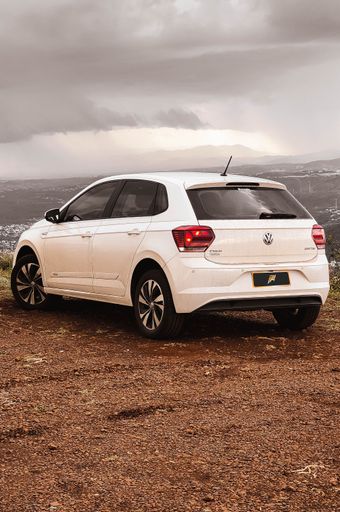 A white Volkswagen Polo Comfortline, parked on a hill under a gloomy gray sky