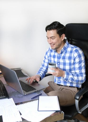 A Caucasian man working with a computer and notebook in the office
