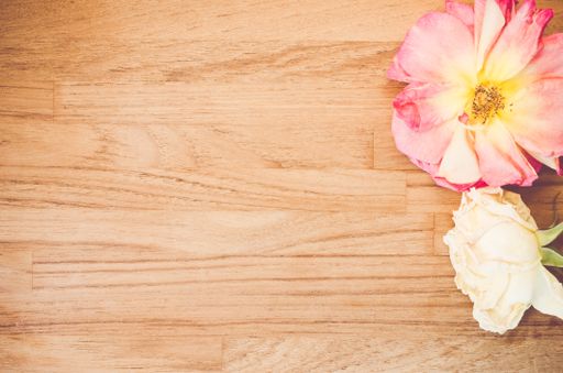 A top view closeup of a cosmos flower and a white rose on a wooden table